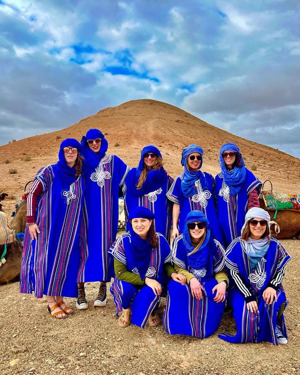Groupe de touristes en tenues berbères traditionnelles bleues dans le désert