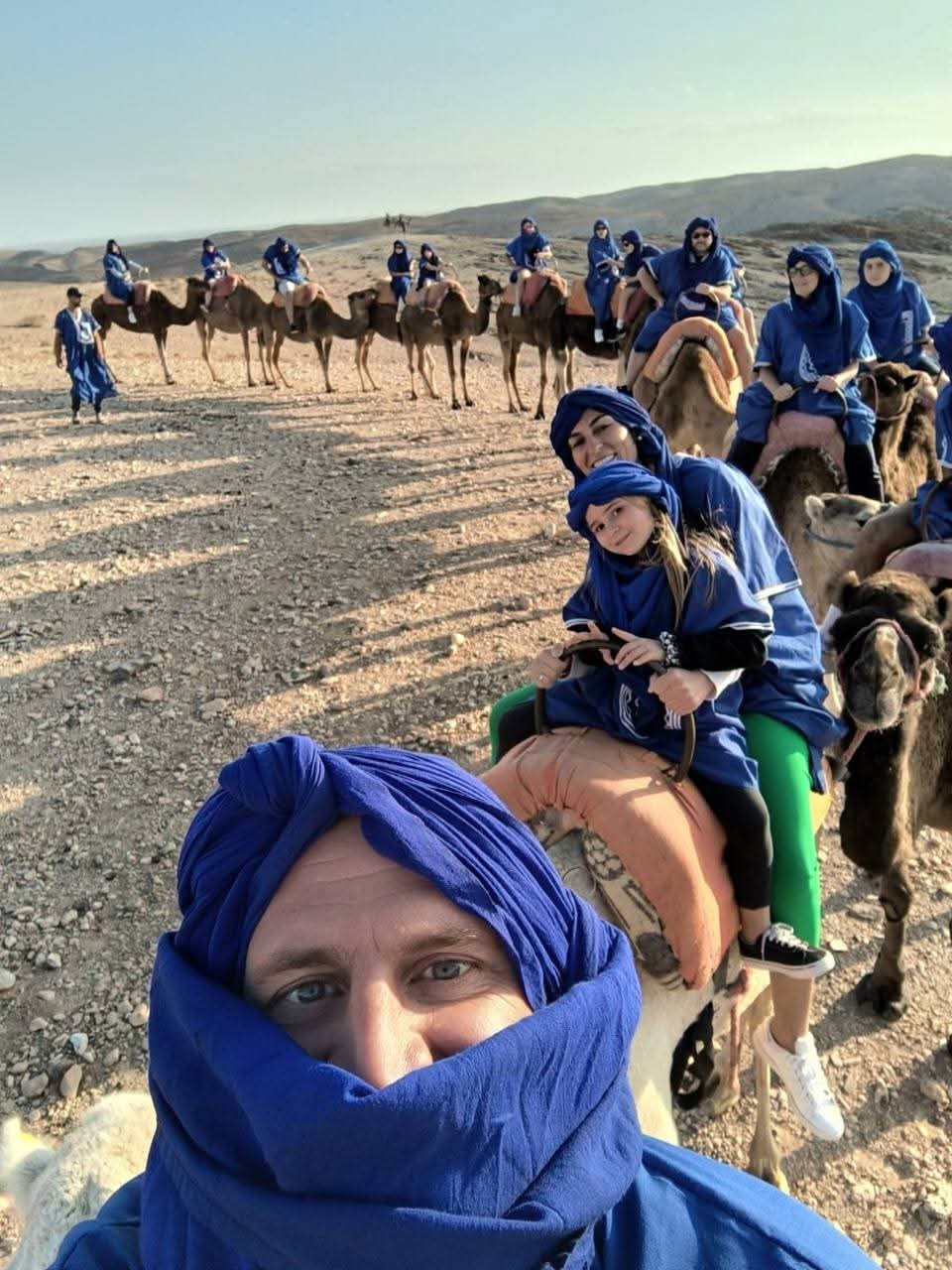 Selfie de groupe en tenues berbères bleues sur des chameaux