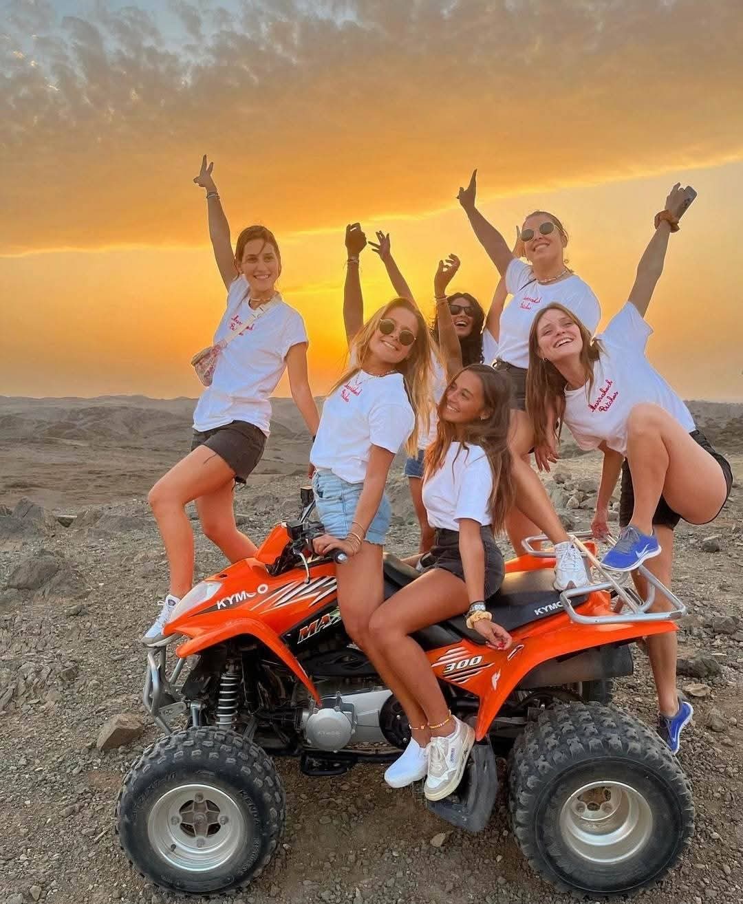 Groupe de femmes célébrant sur quad orange au coucher du soleil