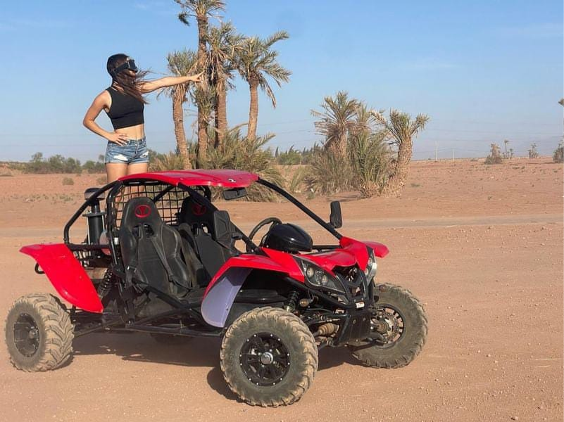 Femme posant avec buggy rouge dans la palmeraie